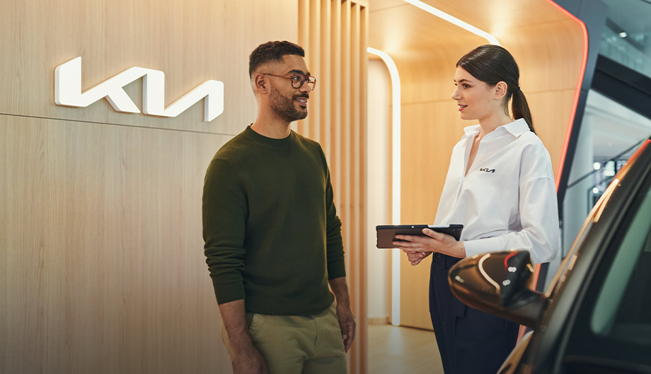 Gespräch zwischen Kunde und Verkaufsberaterin bei einem Kia Händler vor Ort